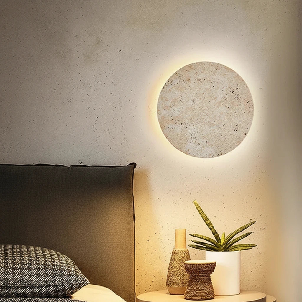Wabi-Sabi Travertine Stone Wall Sconce in warm light 3000k beside a bed