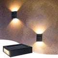 Solar Up & Down Outdoor Wall Lamp in warm white beside a bed